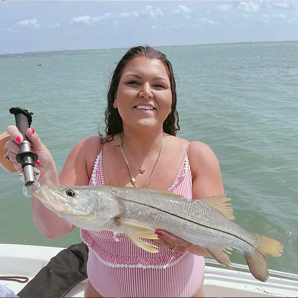 Katelynn Gibbons holding up a fish while on a boat