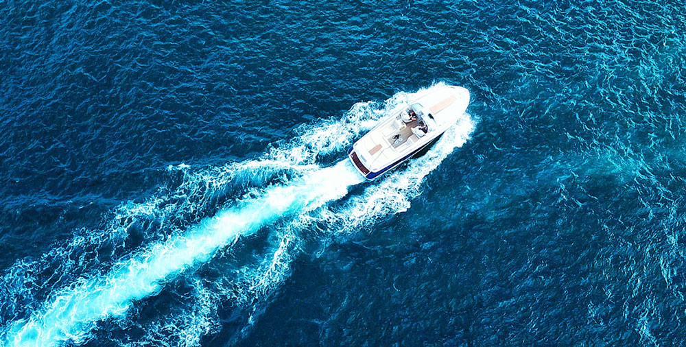 An arial view of a power boat speeding through the ocean