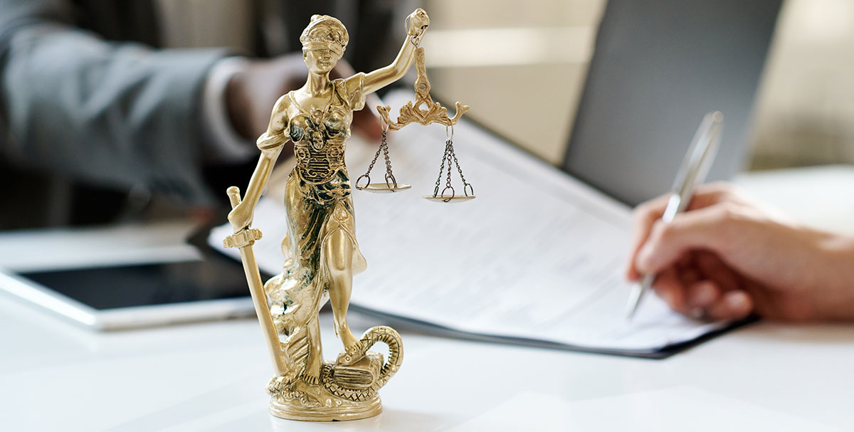 Lady Justice with two people signing documents in the background